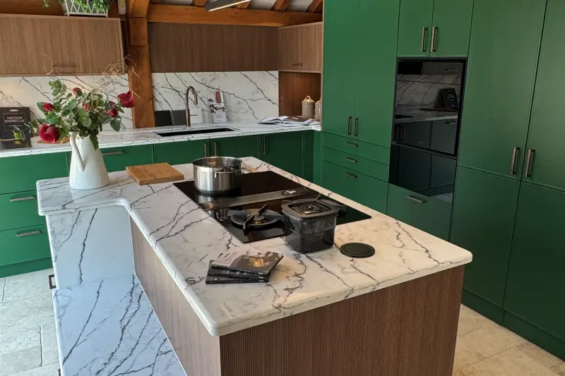 The BORA room in our Hawkhurst showroom: a marble island with a BORA cooktop extractor, beside green cabinets with a built-in oven