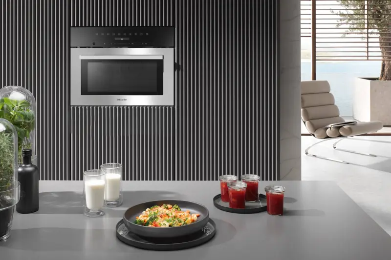 A Miele compact oven built into a black fluted wall
