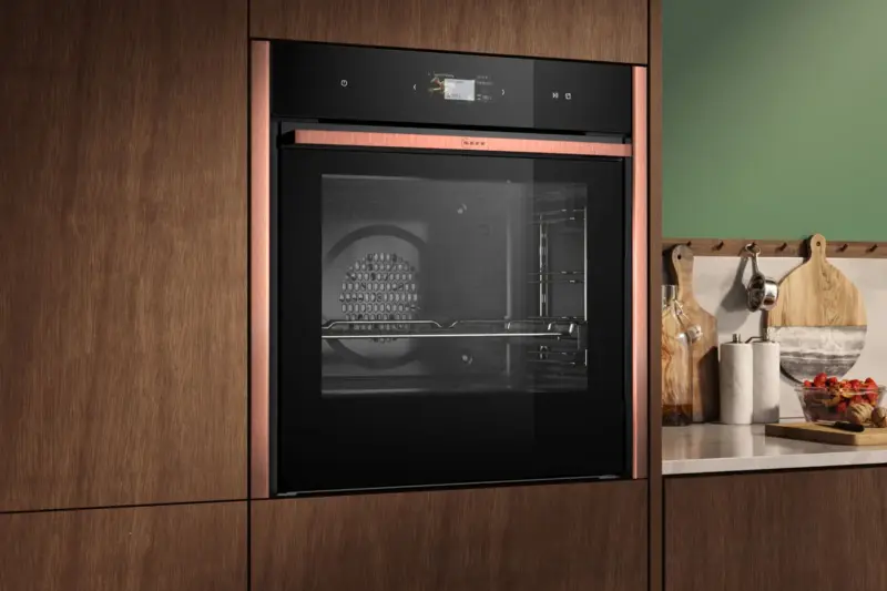 A NEFF built-in oven with copper trim in walnut cabinetry