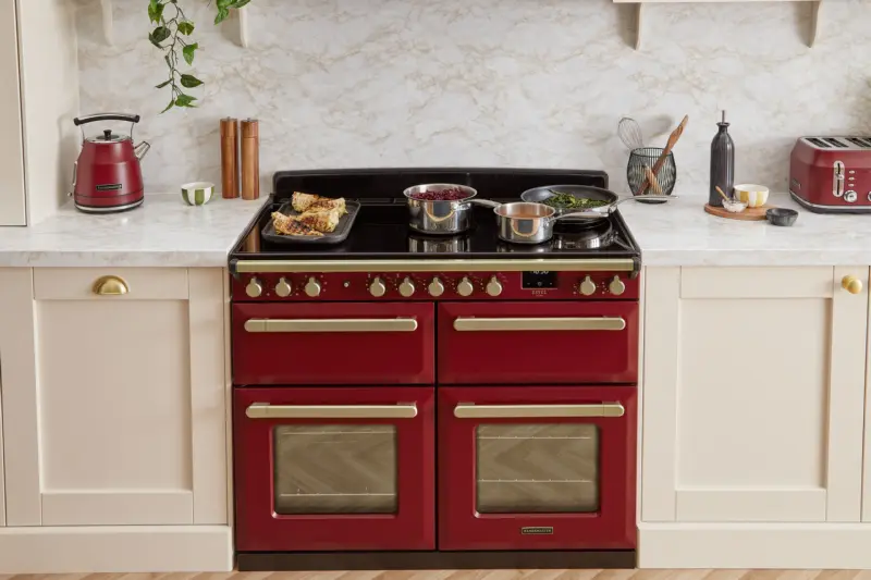 A red Rangemaster Estel range cooker with brass handles in a cream kitchen