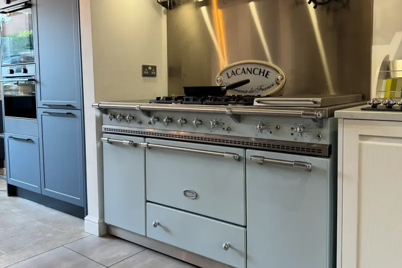 The Lacanche display in our Hawkhurst showroom: a pale blue Lacanche range cooker in front of a stainless steel splashback